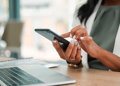 Person sitting at a computer typing something into their cellphone